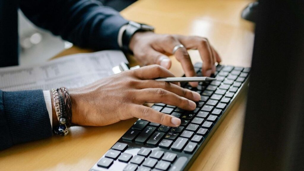 8867210 Close-up of hands typing on keyboard in an office setting, showcasing work professionalism.