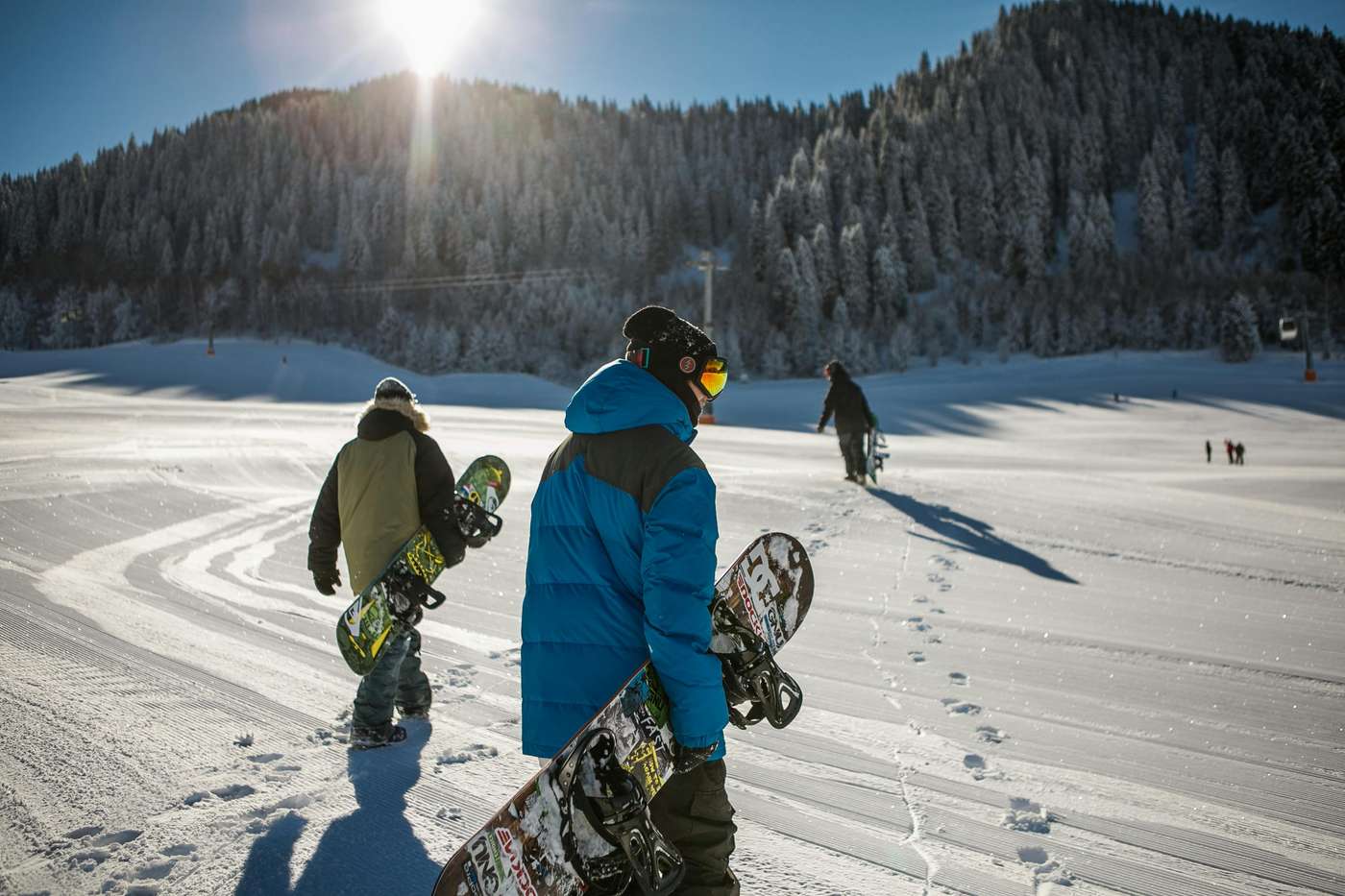 848612 Group of snowboarders walking up a snowy ski slope during a sunny winter day in the mountains.